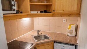 A compact kitchen with a built-in microwave, a coffee maker, and a dishwasher.