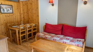 Una habitació acollidora amb un sofà de fusta, una taula de dinar de fusta amb cadirees, i una taula de centre de fusta.