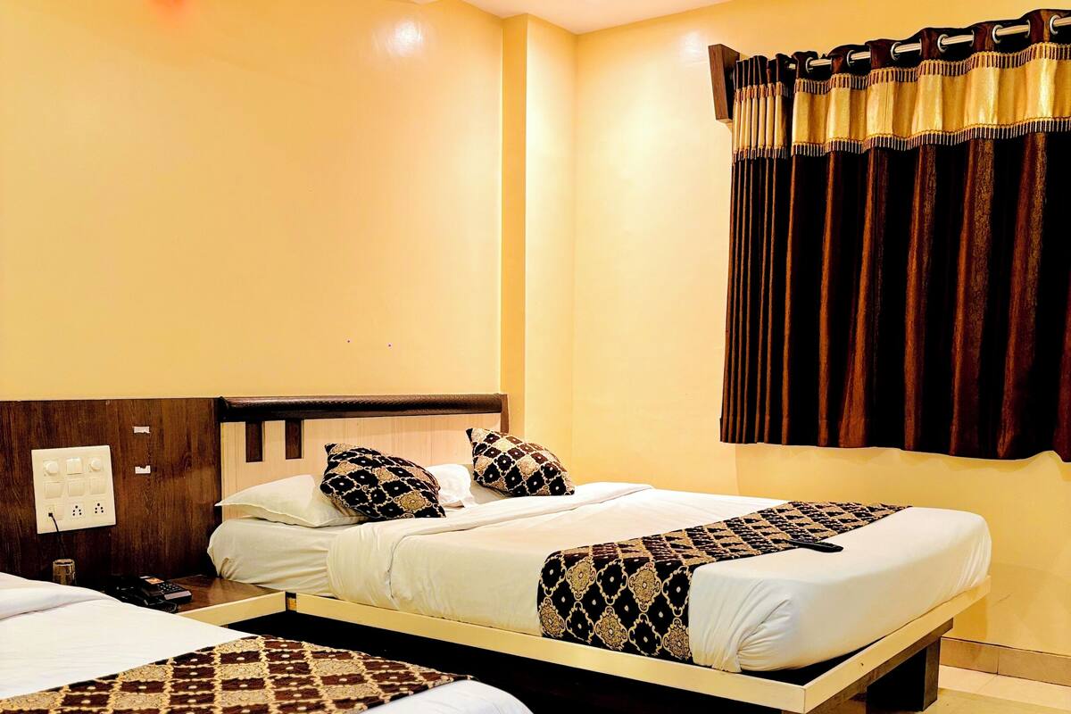 A hotel room with two single beds, a ceiling fan, and a window with curtains.