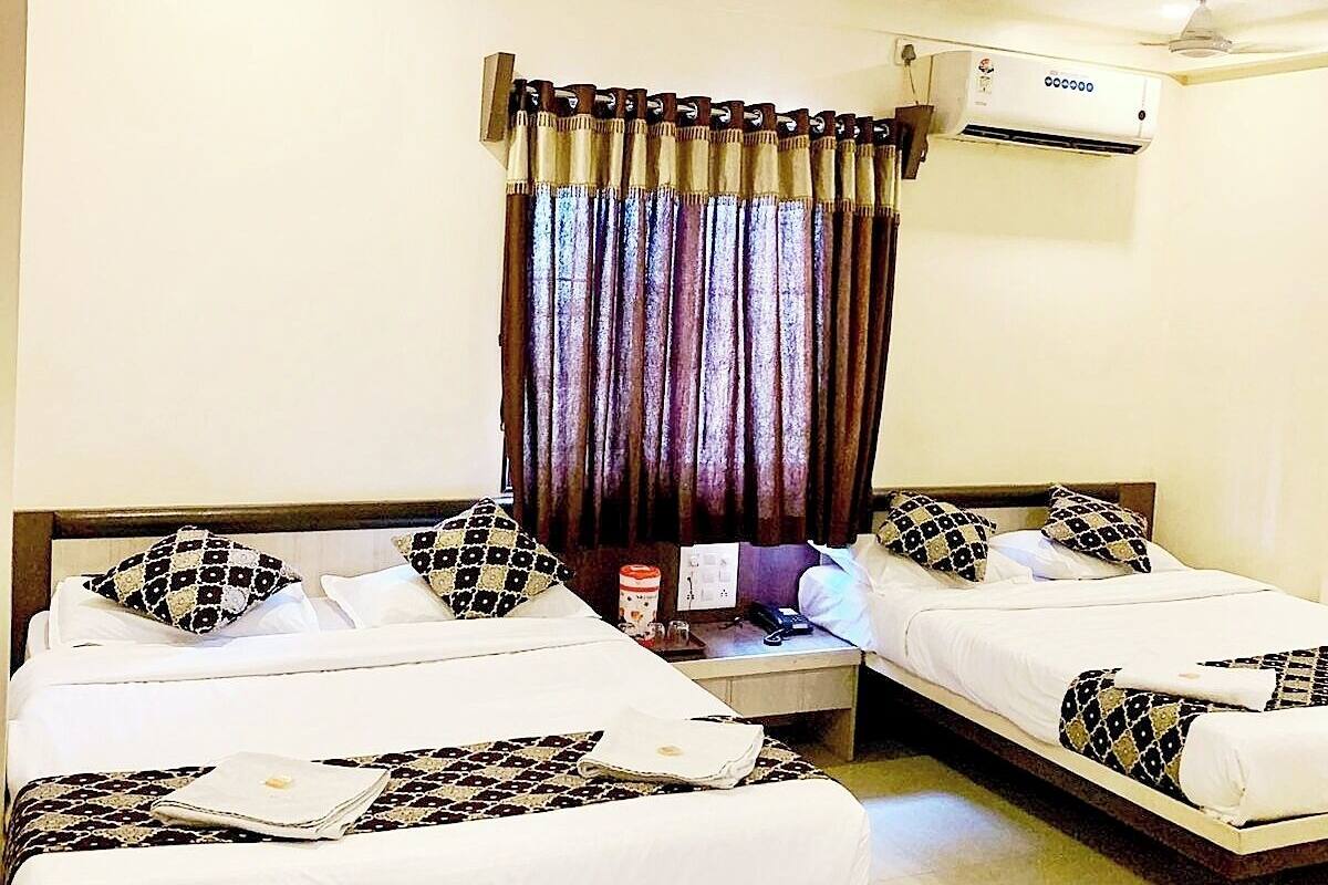 A hotel room with two single beds, a ceiling fan, an air conditioning unit, and a curtain.
