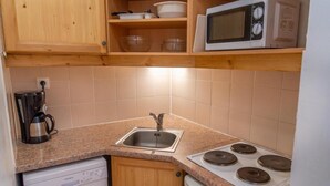 Cocina compacta con pileta, estufa, microondas y lavavajillas.