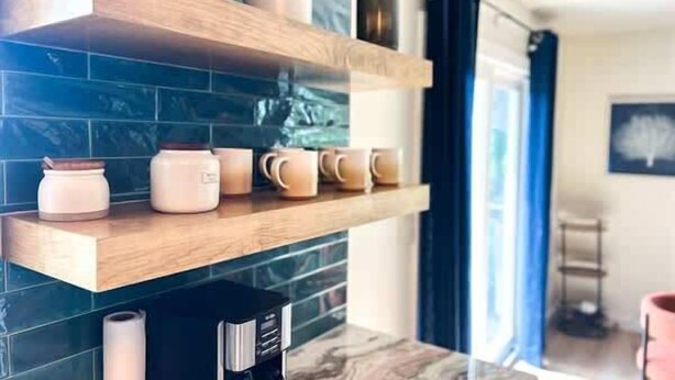 A kitchen with wooden shelves, a coffee machine, and a roll of paper towels.