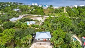 A coastal property with a large house, a swimming pool, and dense tropical vegetation.