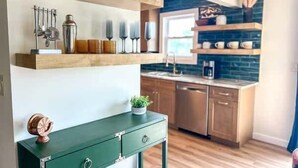 A kitchen with wooden shelves, a green table, and a coffee machine.