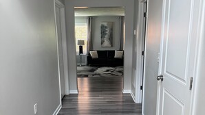 A hallway with a wooden floor, white walls, and a door on the right.