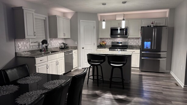 A modern kitchen with white cabinets, stainless steel appliances, and a central island with bar stools.