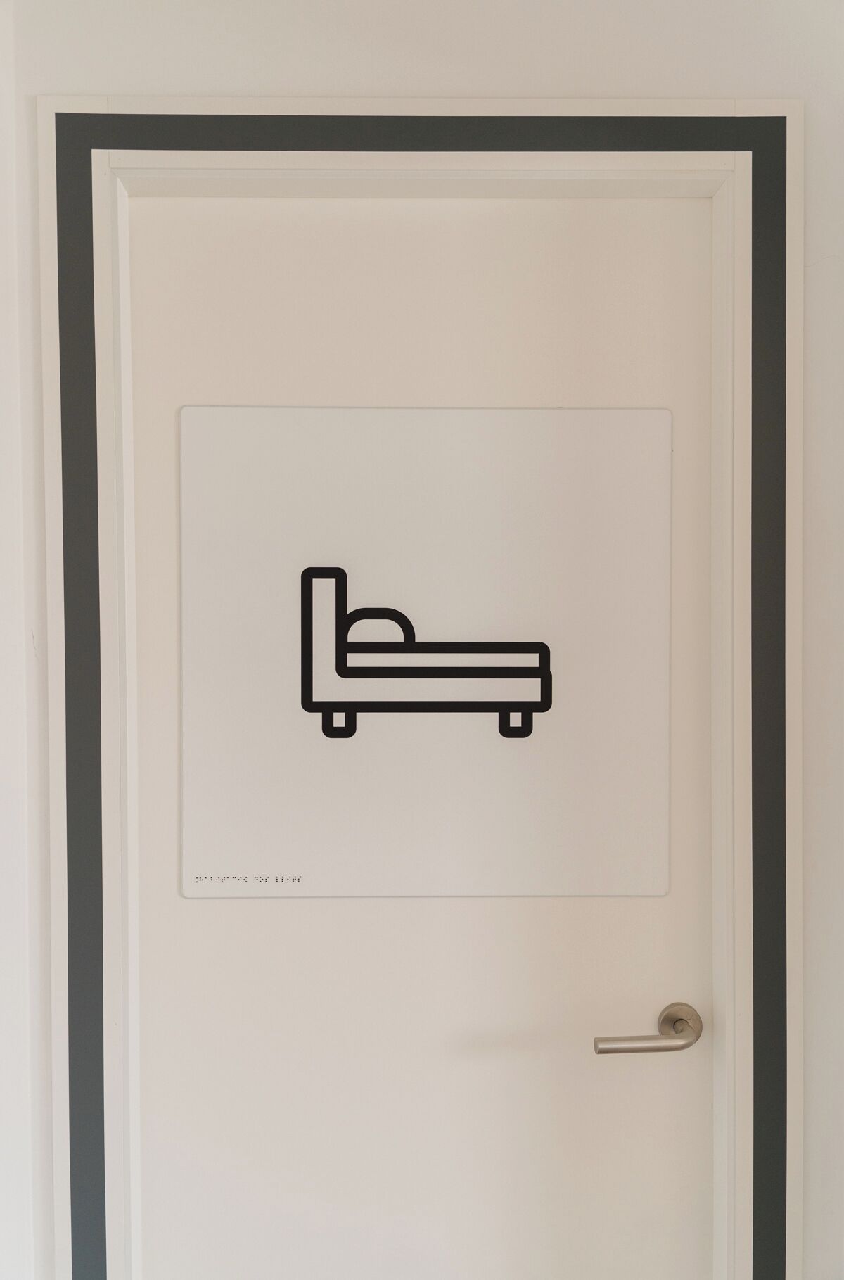A door with a bed icon, a door handle, and a small text box with illegible text.