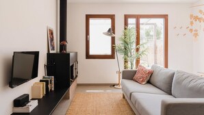 A modern living room with a flat-screen TV, books, a fireplace, a sofa, and a large window. - La Figuera, house at Ultramort (Ultramort)