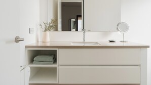 A modern bathroom with a white vanity, a mirror, and a potted plant. - La Figuera, house at Ultramort (Ultramort)