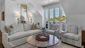 A spacious living room with a high ceiling, large windows, and a view of the outdoors.