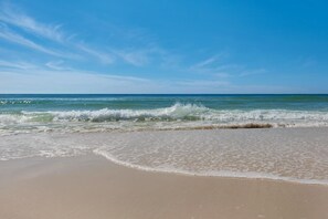Una playa con olas acercándose a la orilla bajo un cielo despejado.