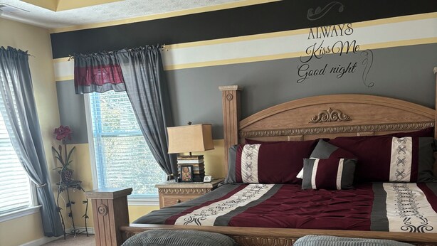 A bedroom with a large bed, a nightstand, a lamp, and a decorative sign on the wall. - 4-bedroom house in charming Union City near airport  (Union City)