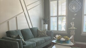 A living room with a green sofa, a white coffee table, and a decorative vase. - 4-bedroom house in charming Union City near airport  (Union City)