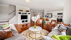 A modern living room with a round coffee table, sofas, and a kitchen in the background.