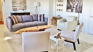 Ein modernes Wohnzimmer mit einem grauen Sofa, einem weißen Sessel, einem Holztisch und einem gemusterten Teppich.
