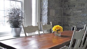 A wooden dining table with chairs, a potted plant, and a vase with flowers. - Luxury Limestone Suite is a Home Away from Home (KIngston)