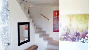A staircase with a wooden handrail, a framed mirror, and a colorful abstract painting on the wall. - 18th Century Luxury Suite with Rustic Charm (KIngston)