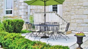 A patio with a table and chairs, a green umbrella, and a potted plant. - 18th Century Luxury Suite with Rustic Charm (KIngston)