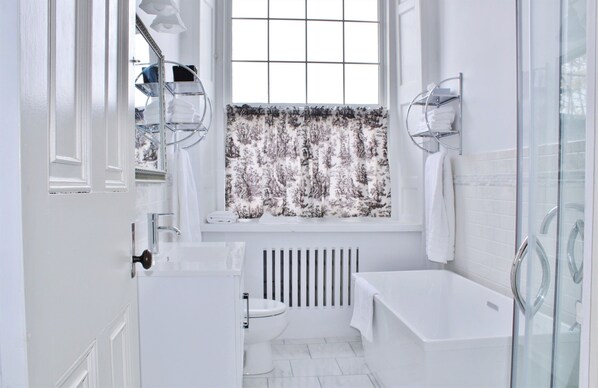A modern bathroom with a bathtub, a toilet, and a window with a view of a snowy landscape.