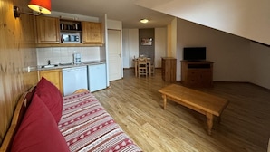 A compact living space with a kitchenette, a dining area, and a seating area with a sofa and a table.