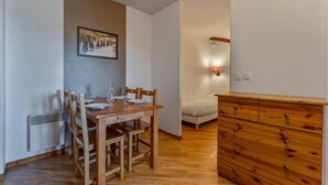 Ein Essbereich mit Holztisch und -stühlen, einem weißen Heizkörper, einer Holzkommode und einer Wandleuchte.