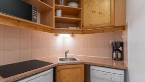 A compact kitchen with wooden cabinets, a black induction cooktop, a Bosch dishwasher, and a coffee maker. - 40m from ski slopes, 3rd floor, fitness, swimming pool, sauna, tv, ski locker, 35m², Les Orres (Les Orres)