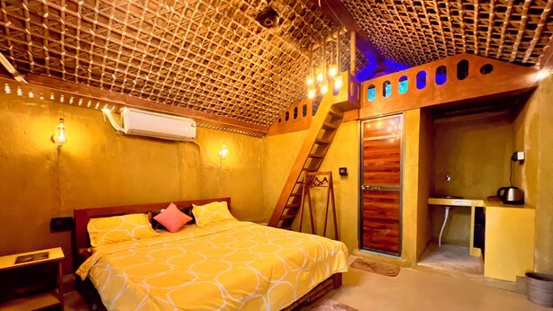A bedroom with a bed, a desk, and a staircase. - La Pahi Palace (Madhubani)
