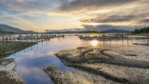 A marina with boats docked, calm water, and a sunset in the background. - Stylish Stay by Harbor | Walkable Hotspot (Juneau)