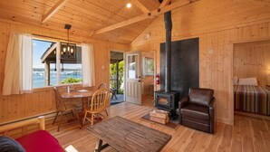 Ein gemütliches Blockhaus-Interieur mit Holzboden, Kamin, Essbereich und Blick auf das Wasser.