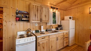 A wooden-paneled kitchen with a stove, sink, and refrigerator.