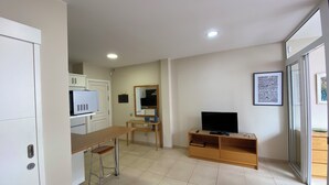 A modern kitchen with white cabinets, a microwave, and a wooden dining table with two stools. - Las Canteras Beach (Las Palmas de Gran Canaria)