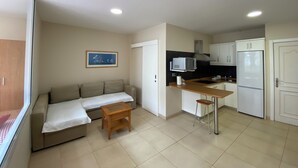 A compact living space with a kitchenette, a sofa, a small table, and a ceiling light. - Las Canteras Beach (Las Palmas de Gran Canaria)