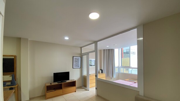 A living room with a television, a wooden cabinet, a glass coffee table, and a sofa. - Las Canteras Beach (Las Palmas de Gran Canaria)