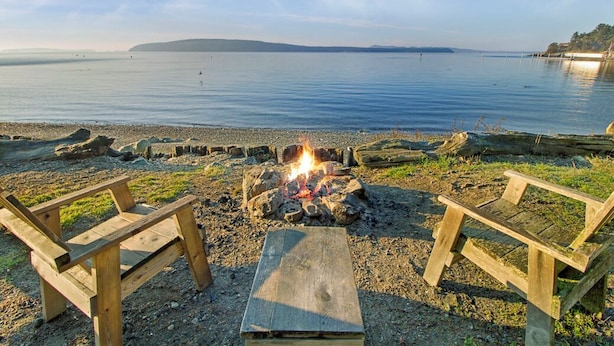 Une plage avec un foyer et deux chaises en bois.