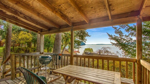 Un muelle de madera con una mesa y sillas, con vistas a un lago.