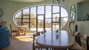 Un coin repas doté d’une grande fenêtre ovale, de meubles en bois et d’un lustre.