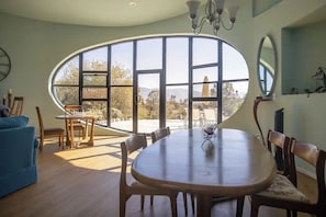 Ein Essbereich mit einem großen, ovalen Fenster, Holzmöbeln und einer Kristallleuchter.