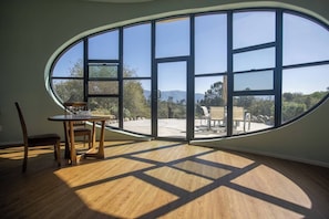 Ein Zimmer mit einem großen, ovalen Fenster, das einen Blick auf eine Terrasse mit Gartenmöbeln bietet.