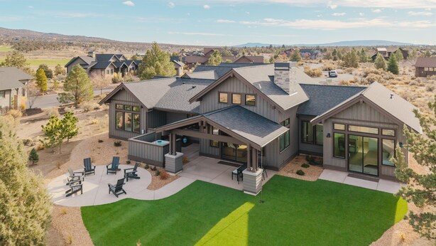 A modern two-story house with a covered patio, a well-maintained lawn, and a view of the surrounding neighborhood.
