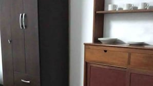 A room with a wooden table, a cabinet, and a shelf with dishes.