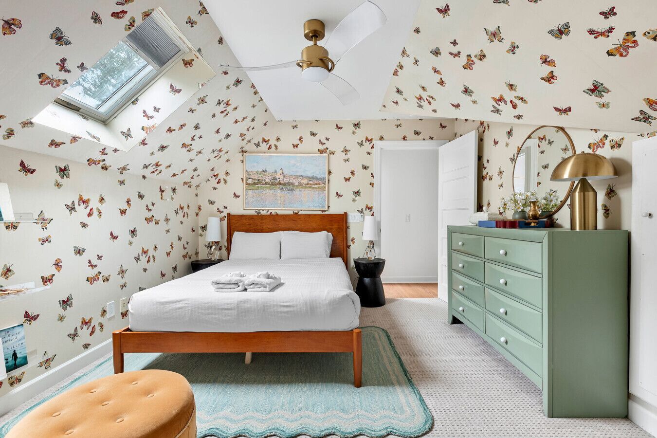 A bedroom with a bed, a dresser, a nightstand, a mirror, and a ceiling fan.