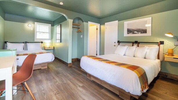 A room with two beds, a desk, and a chair. There is a window, a door, and a picture on the wall. - Dew Duck Inn (Plains)