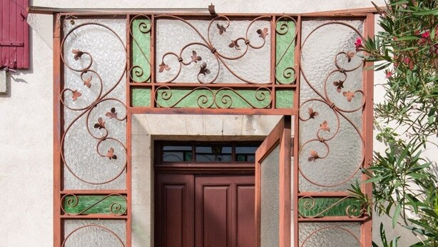 A building entrance with a red door, decorative ironwork, and a tiled pathway. - Le Guiguet - Mas provençal avec piscine pour 10 (Vedene)