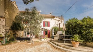 A courtyard with a rustic building, outdoor seating, and potted plants. - Le Guiguet - Mas provençal avec piscine pour 10 (Vedene)