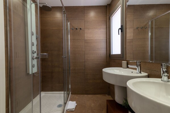 A modern bathroom with a glass-enclosed shower, two sinks, and a large mirror.