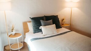 A neatly made bed with a white and gray blanket, multiple pillows, and two bedside tables with lamps. - Langmeil Cottages - Blue Gum (Tanunda)
