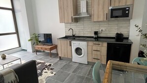 Una cocina moderna con armarios de madera, microondas integrado y lavadora.