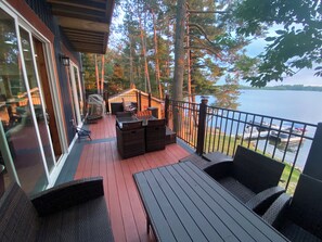 A deck with wicker furniture, a covered grill, and a view of the lake. - Spacious Lakefront Cabin Sleeps up to 14. (Hatley)