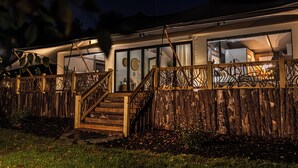 Une maison moderne dotée d’une terrasse en bois, d’un escalier et d’une porte vitrée donnant sur l’intérieur.