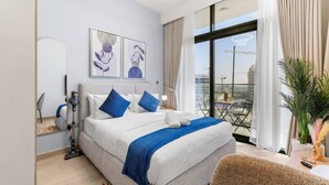 Quarto de hotel moderno com uma cama grande, uma varanda com vista e obras de arte na parede.